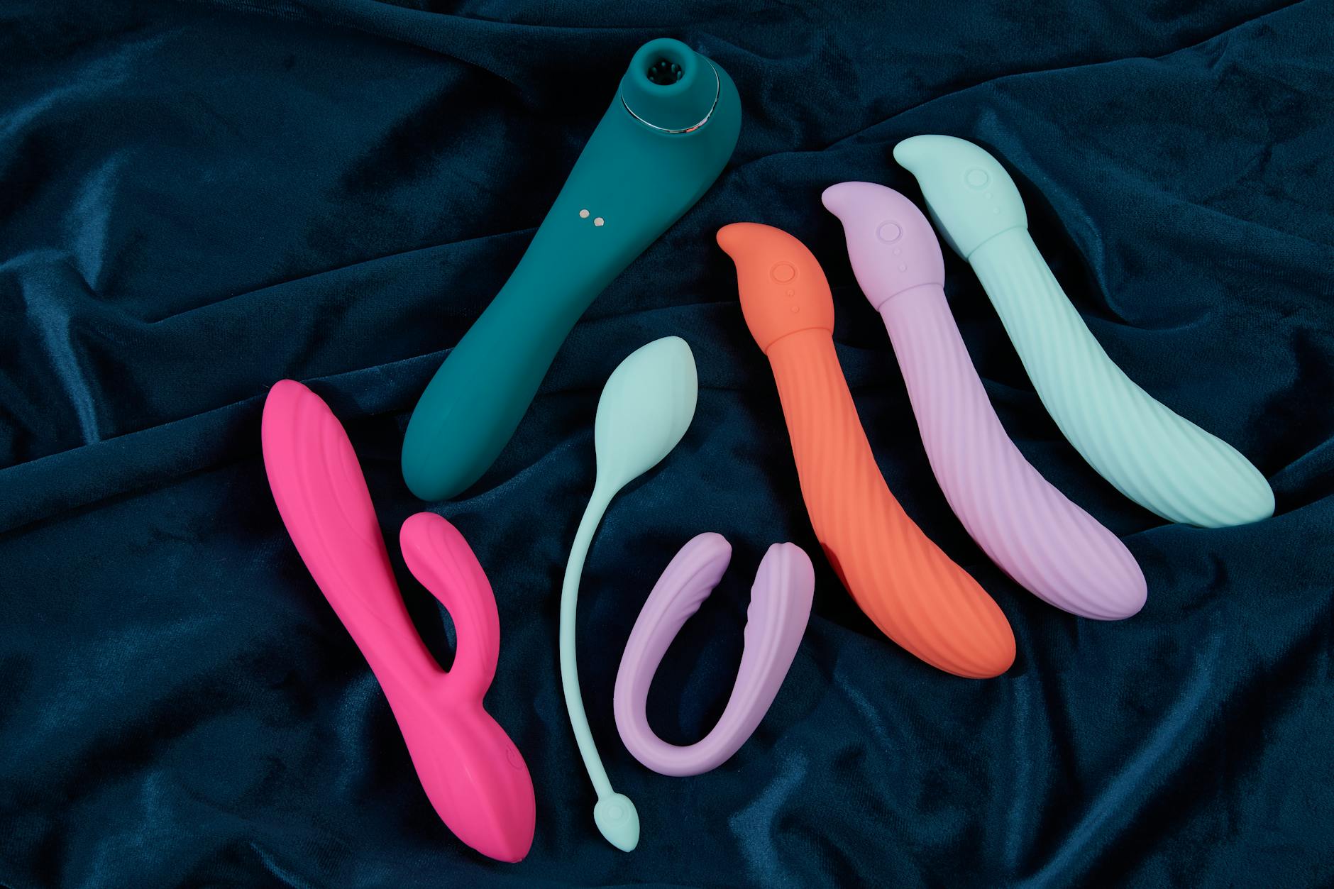 Collection of colorful silicone lemon vibrators and clitoral toys on fabric