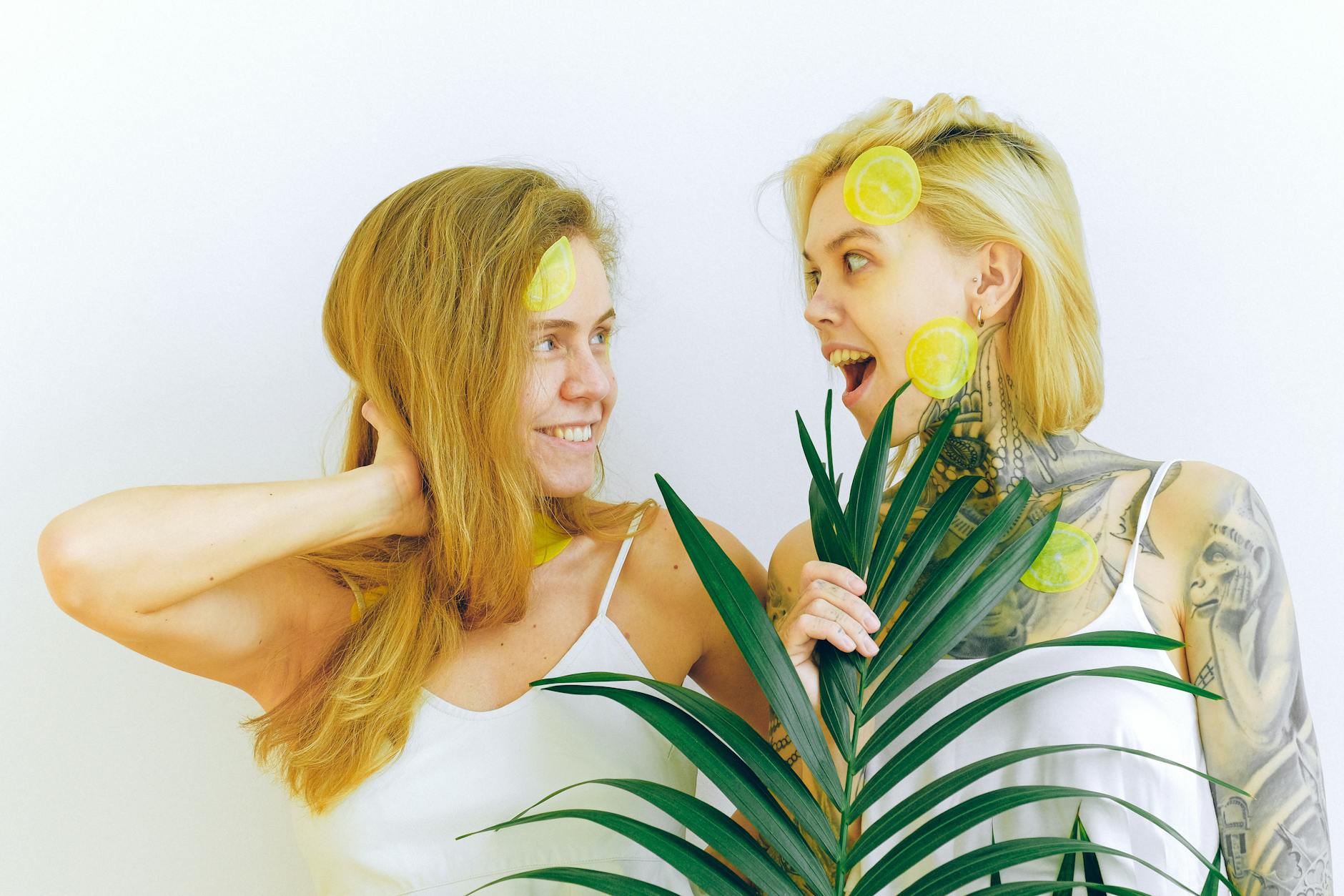 Two women smiling together with vibrant lemon slices, expressing joy and comfort indoors