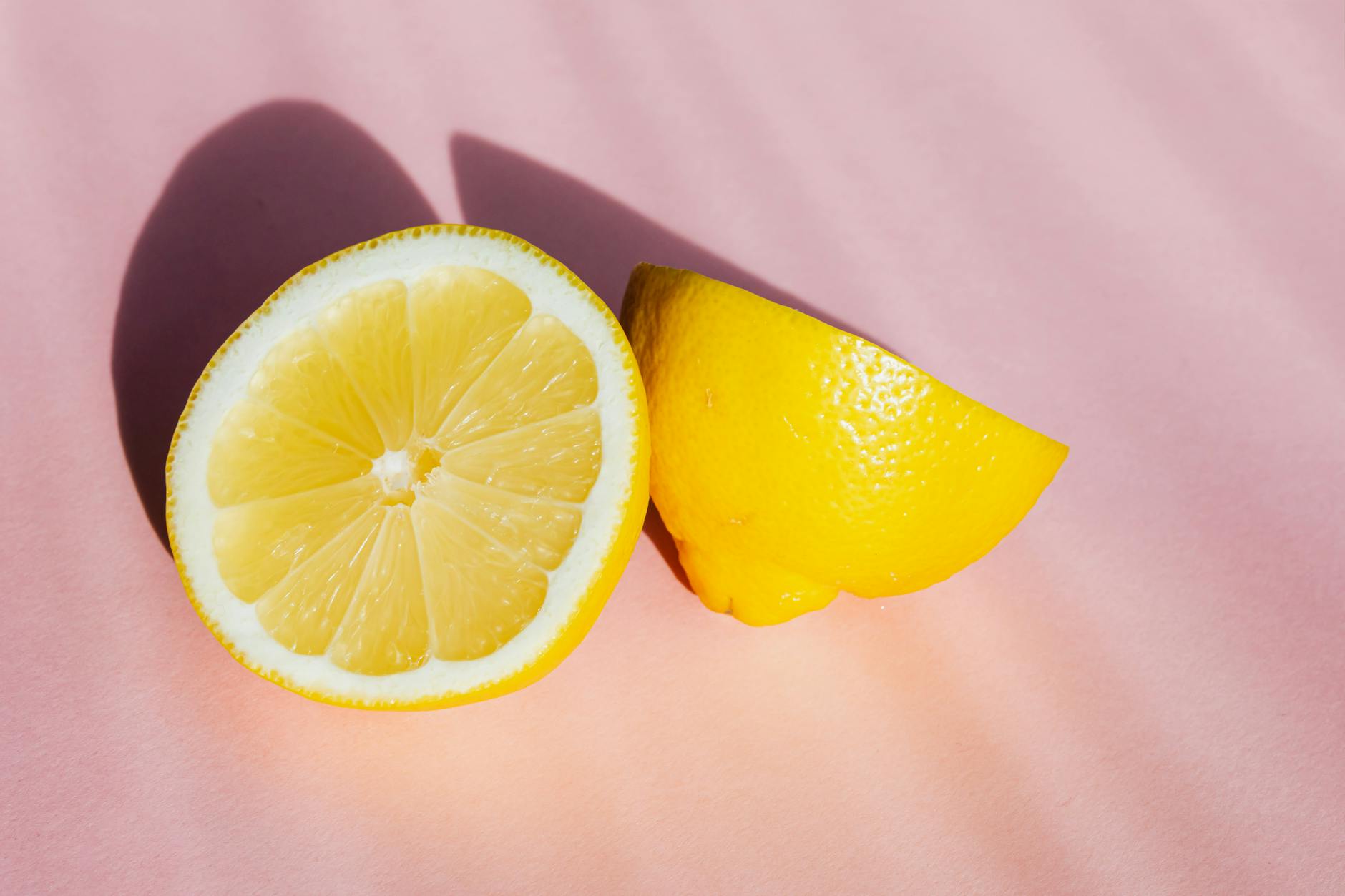 Fresh lemon halves on a pink background in sunlight, symbolizing renewal and fresh starts
