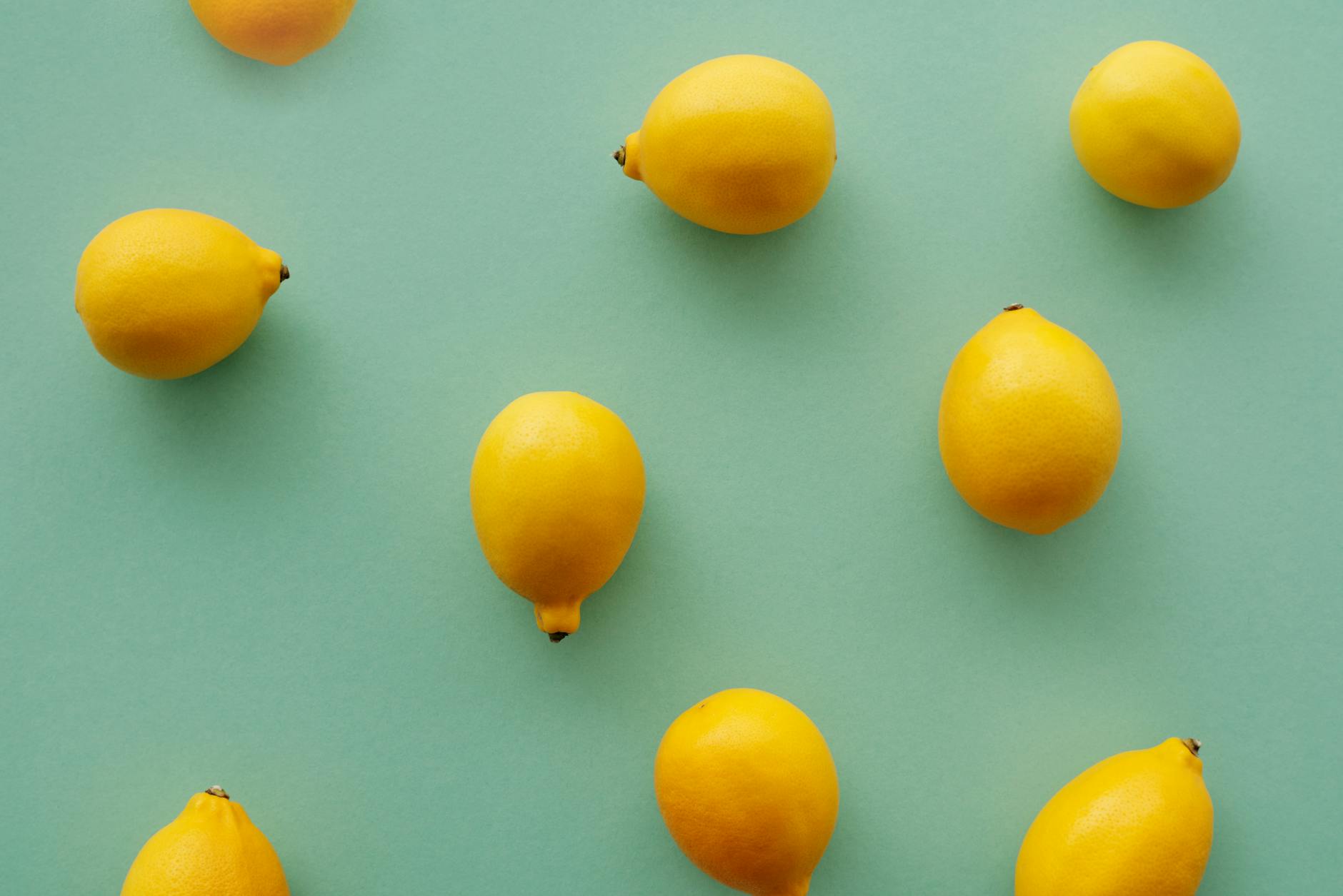 Bright yellow lemons arranged on a pastel green background, symbolizing freshness and renewed sensation