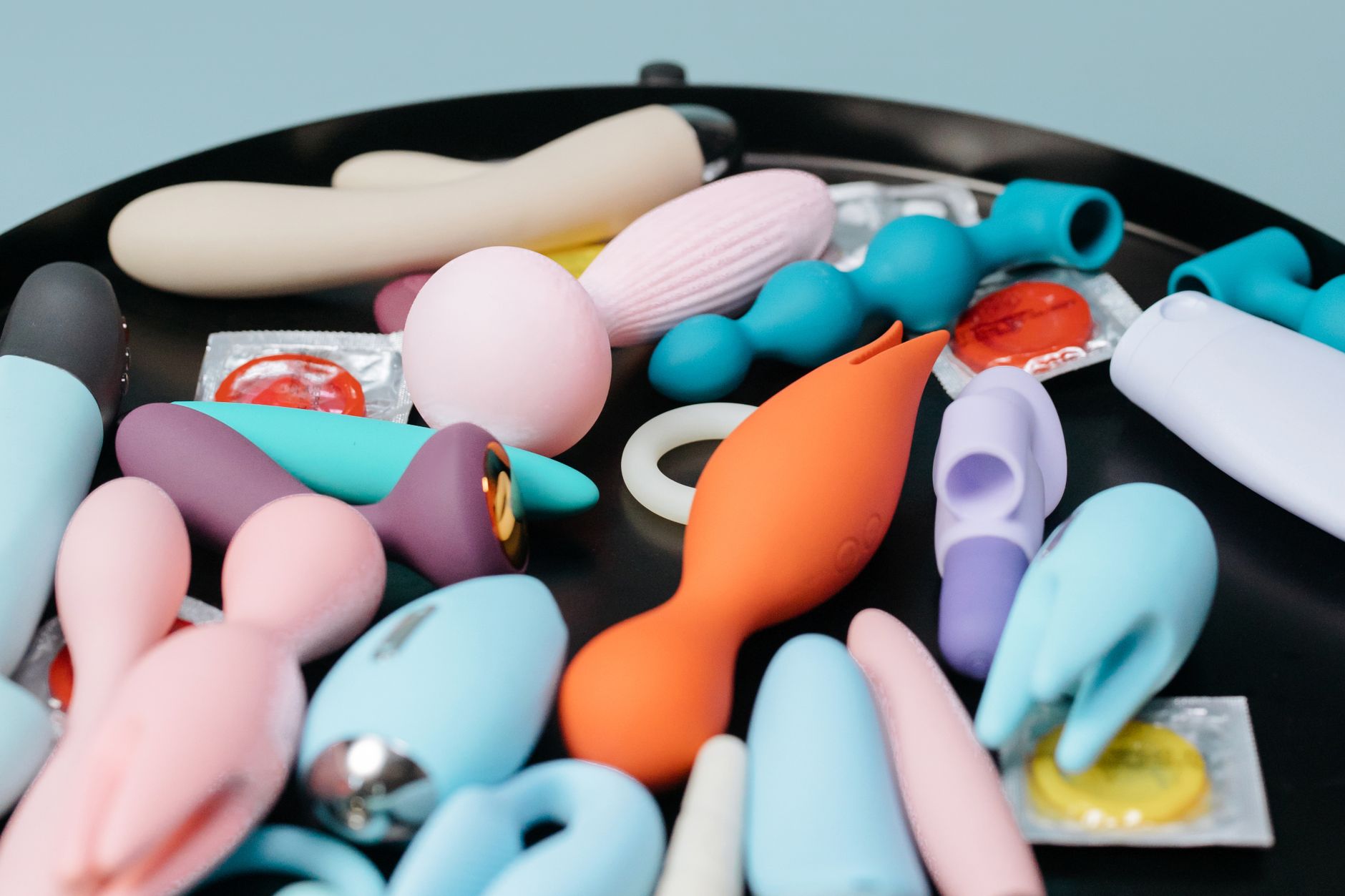Colorful sex toys arranged on a bright yellow surface