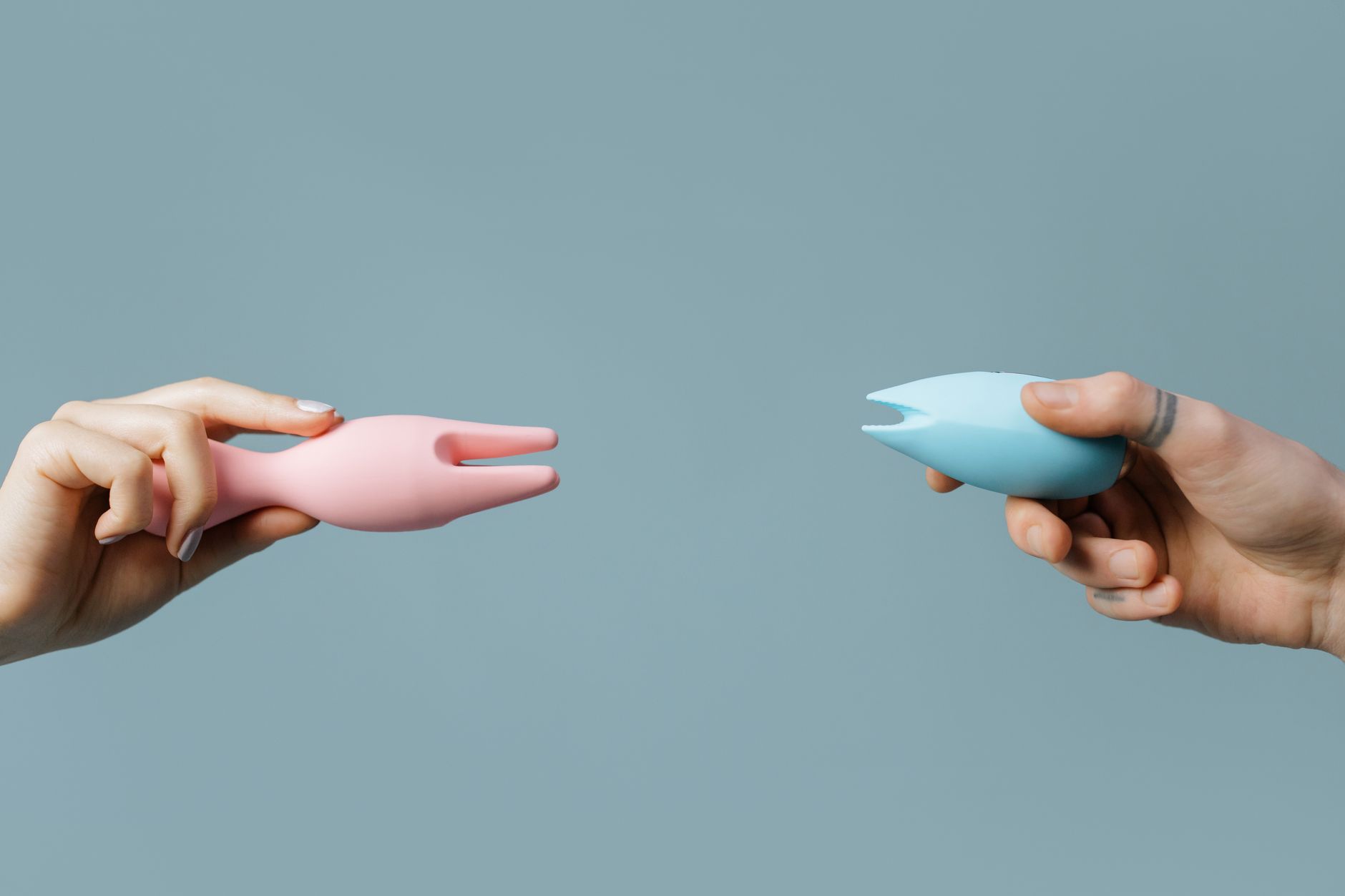 Two hands holding vibrators together against a pastel background, representing reconnection