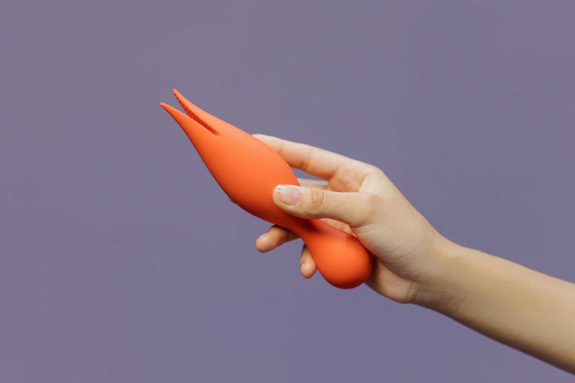 Close-up of hands holding a personal vibrator against a minimalistic backdrop