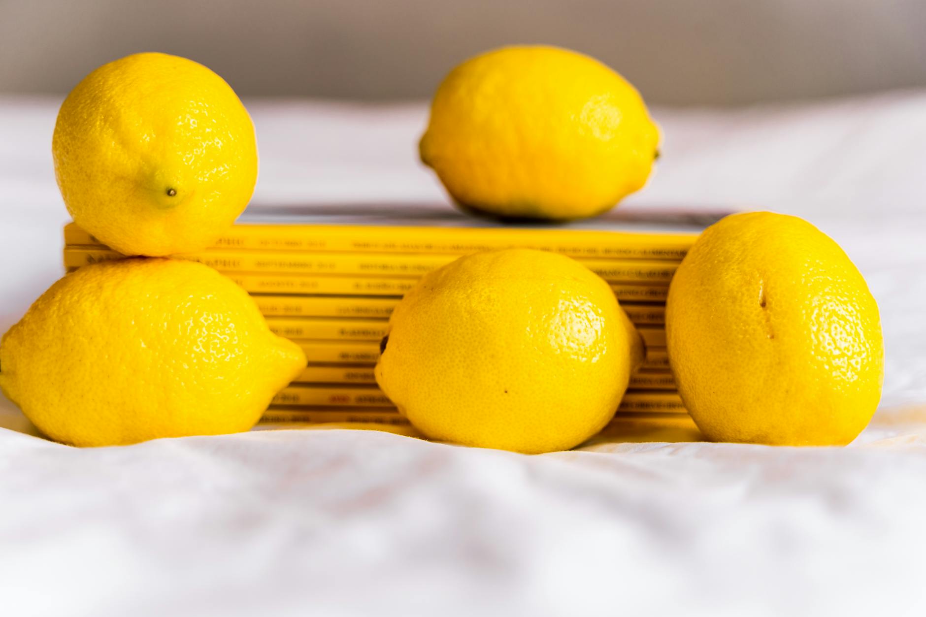 Bright ripe lemons arranged on a vibrant yellow background in studio lighting